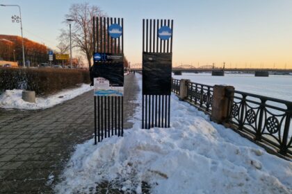 Reklāmas stendi krastmalā Rīgā, ap kuriem sakrājies nenotīrīts sniegs.