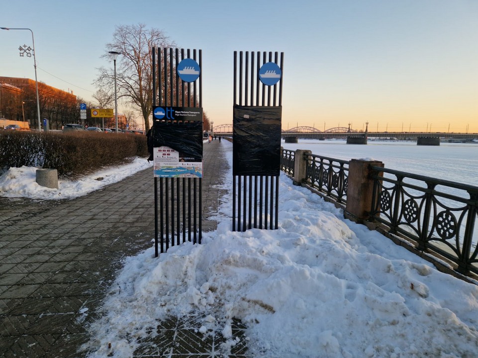 Reklāmas stendi krastmalā Rīgā, ap kuriem sakrājies nenotīrīts sniegs.