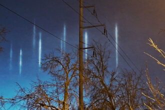Vertikāli gaismas stabi naksnīgajās debesīs virs Bolderājas, Rīgā.